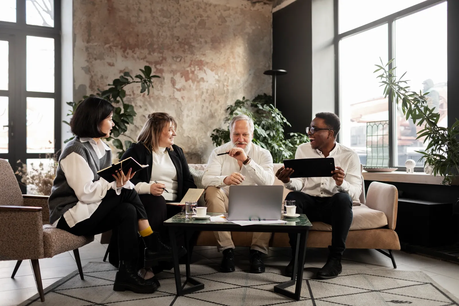 Four people meeting around a laptop in a bright living room