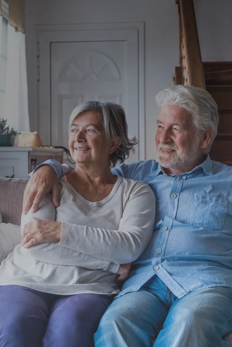 A retired couple sitting together on the sofa in their living room