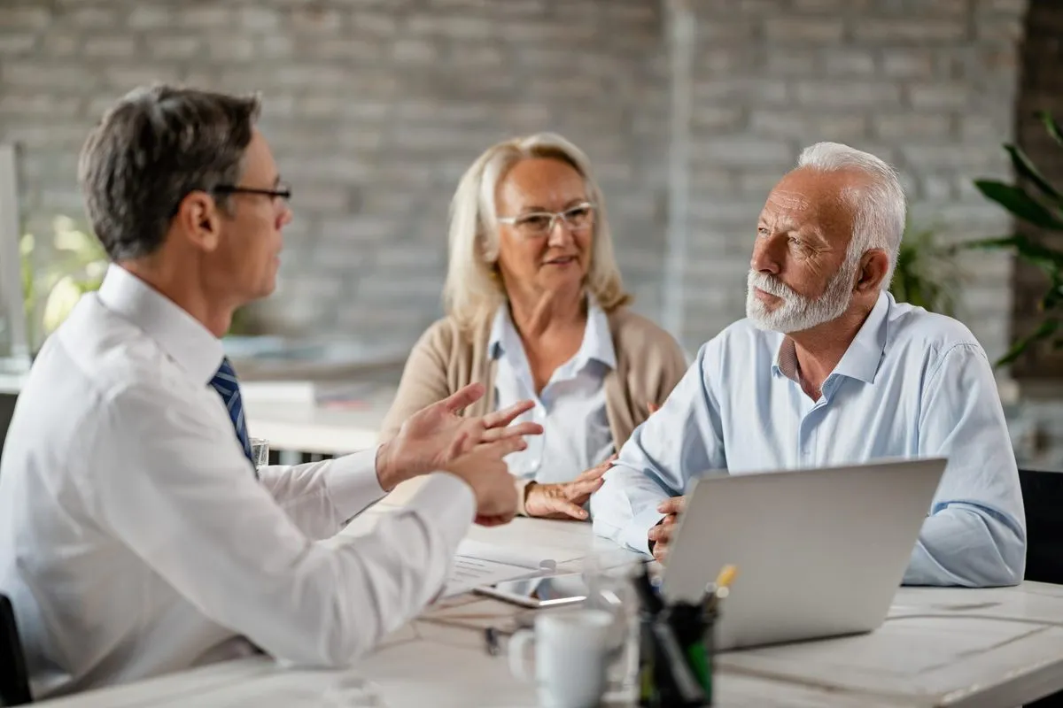 A man in conversation with an older couple across a desk