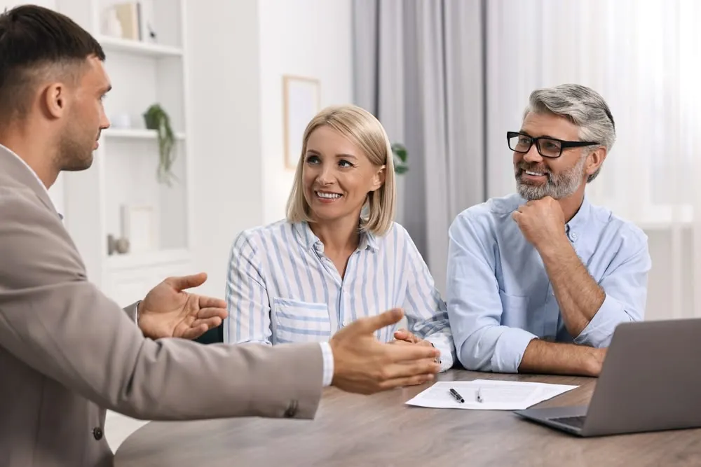 A couple listening as an advisor talks them through paperwork at a table