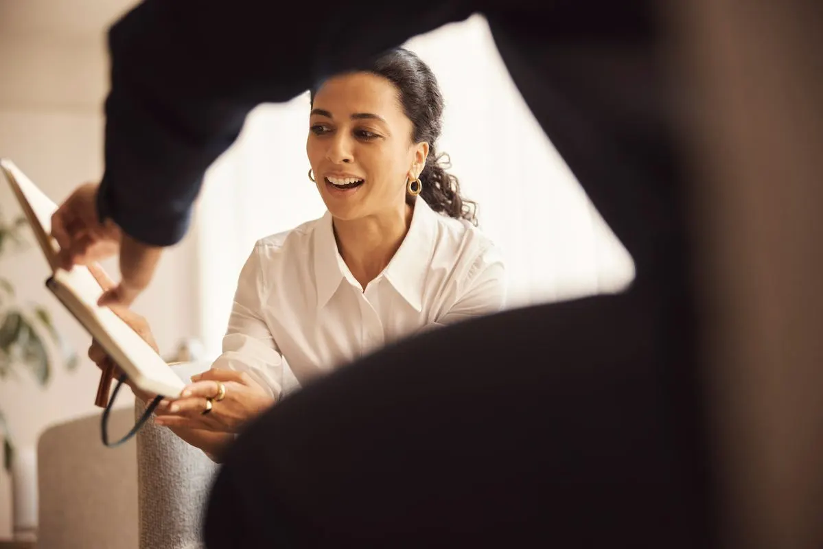 A woman at a desk smiling while reviewing a document