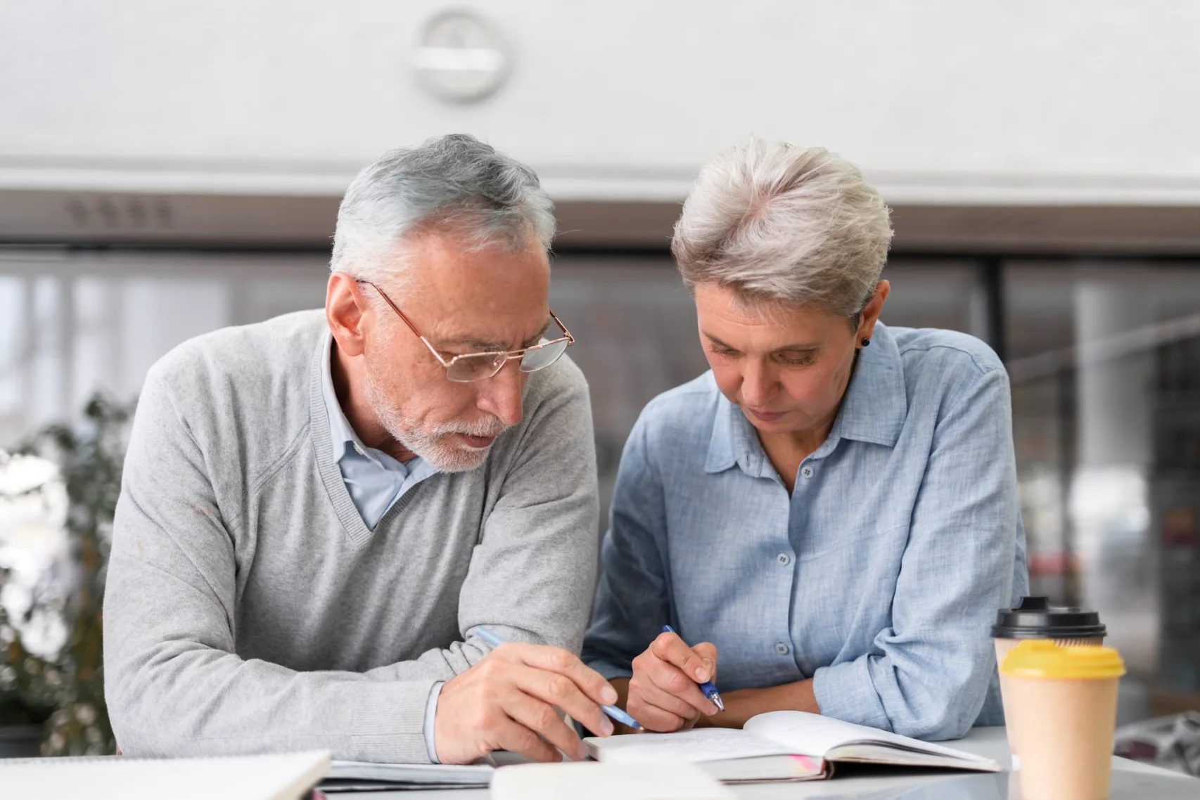 An older couple sitting together at a table, reading through paperwork