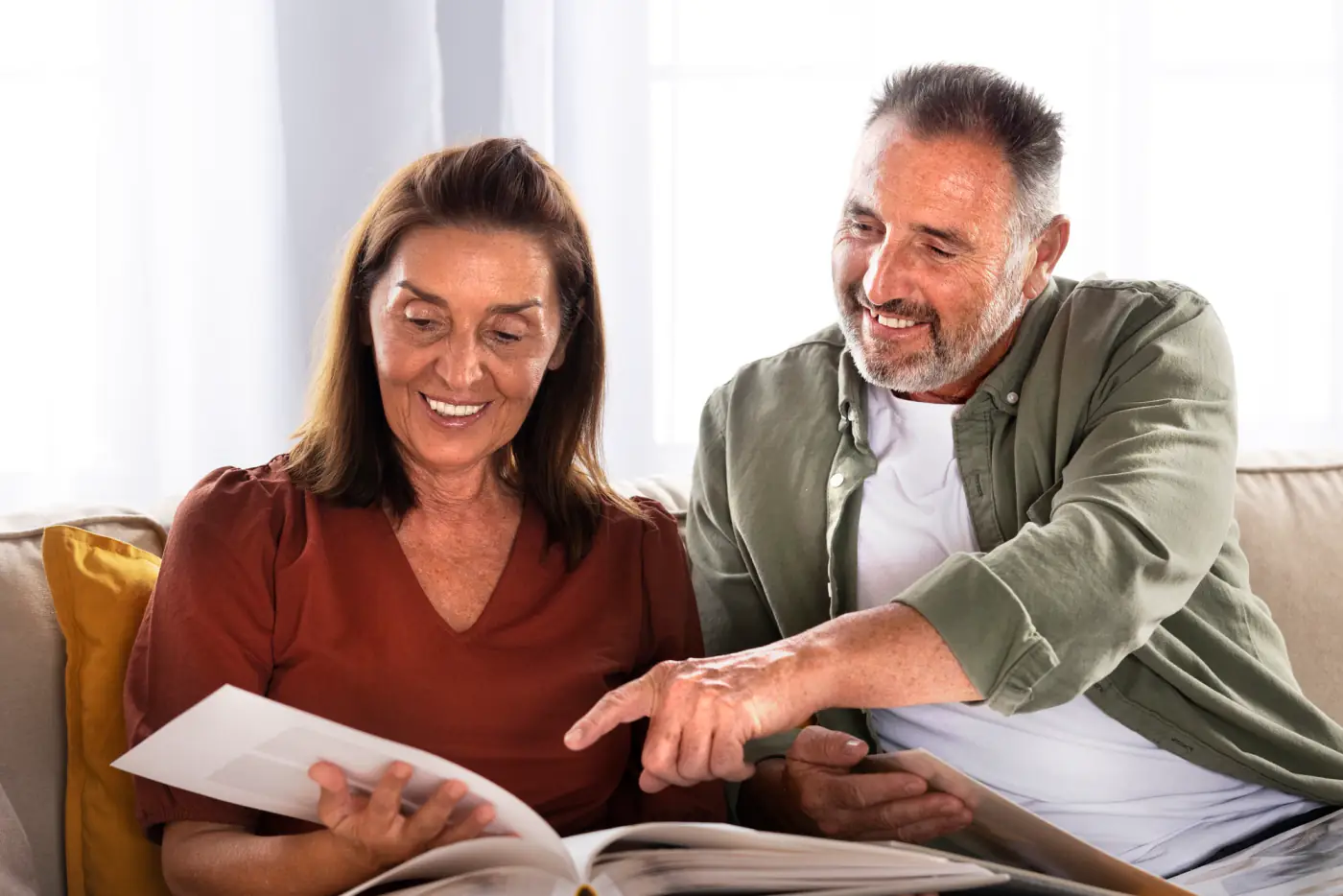 An older couple sitting together on a sofa reading a document