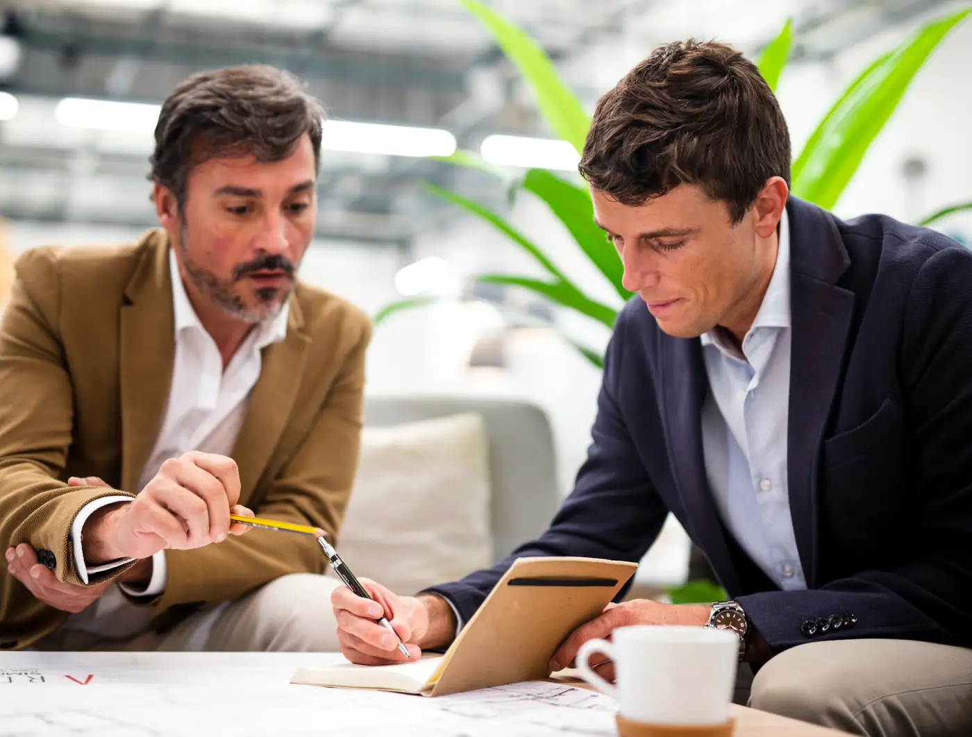 Two men reviewing paperwork and taking notes together at an office table