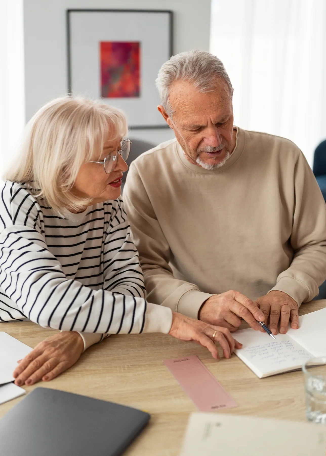 An older couple sitting at a table, reading through paperwork together